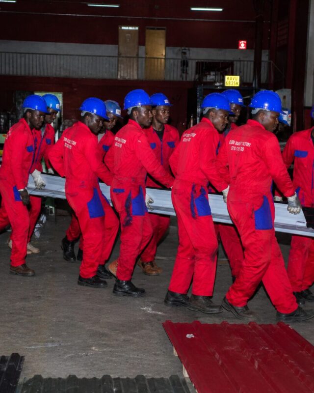 Ruiru Mabati Factory team carrying roofing sheets inside the factory